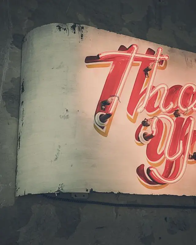 A pink script neon sign reading Thank you